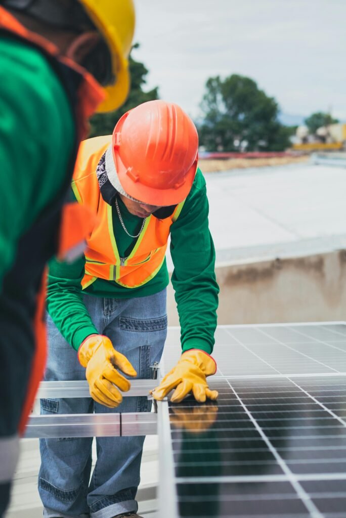 pexels-photo-8853507-8853507 Worker in safety gear installing solar panels on a rooftop.