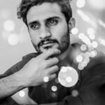 Elegant portrait of a young man in bokeh effect, emphasizing thoughtfulness and style.