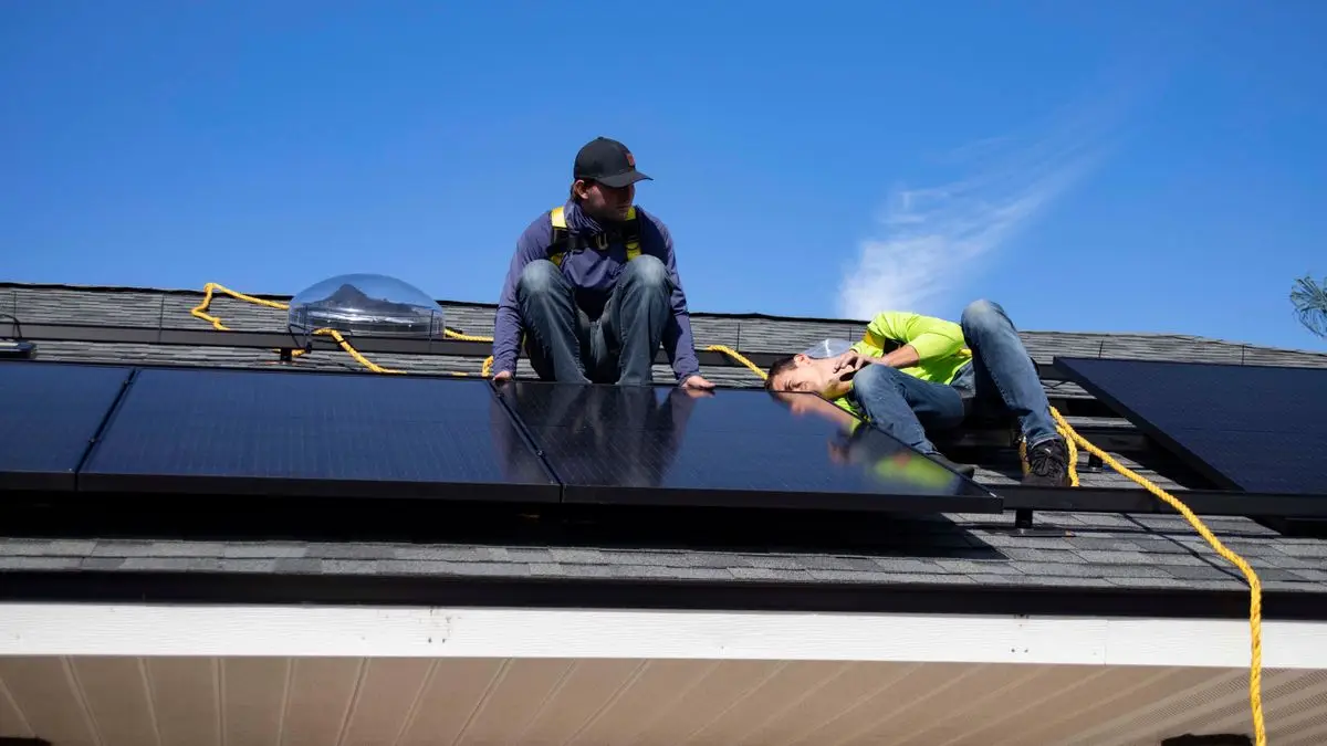 Workers installing solar panels on a roof - parallel inverter
