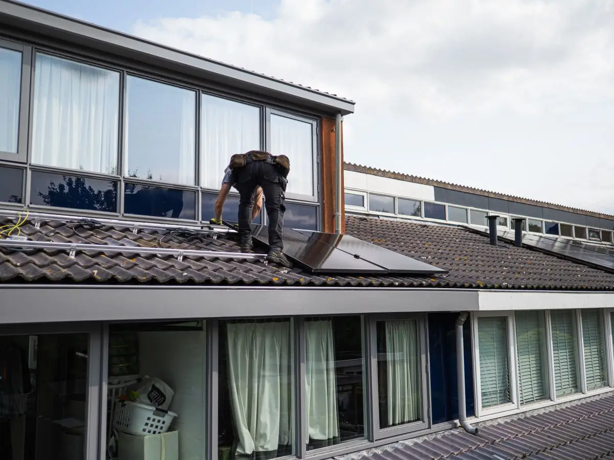 Technician installing solar panels on a rooftop - solar inverter warranty